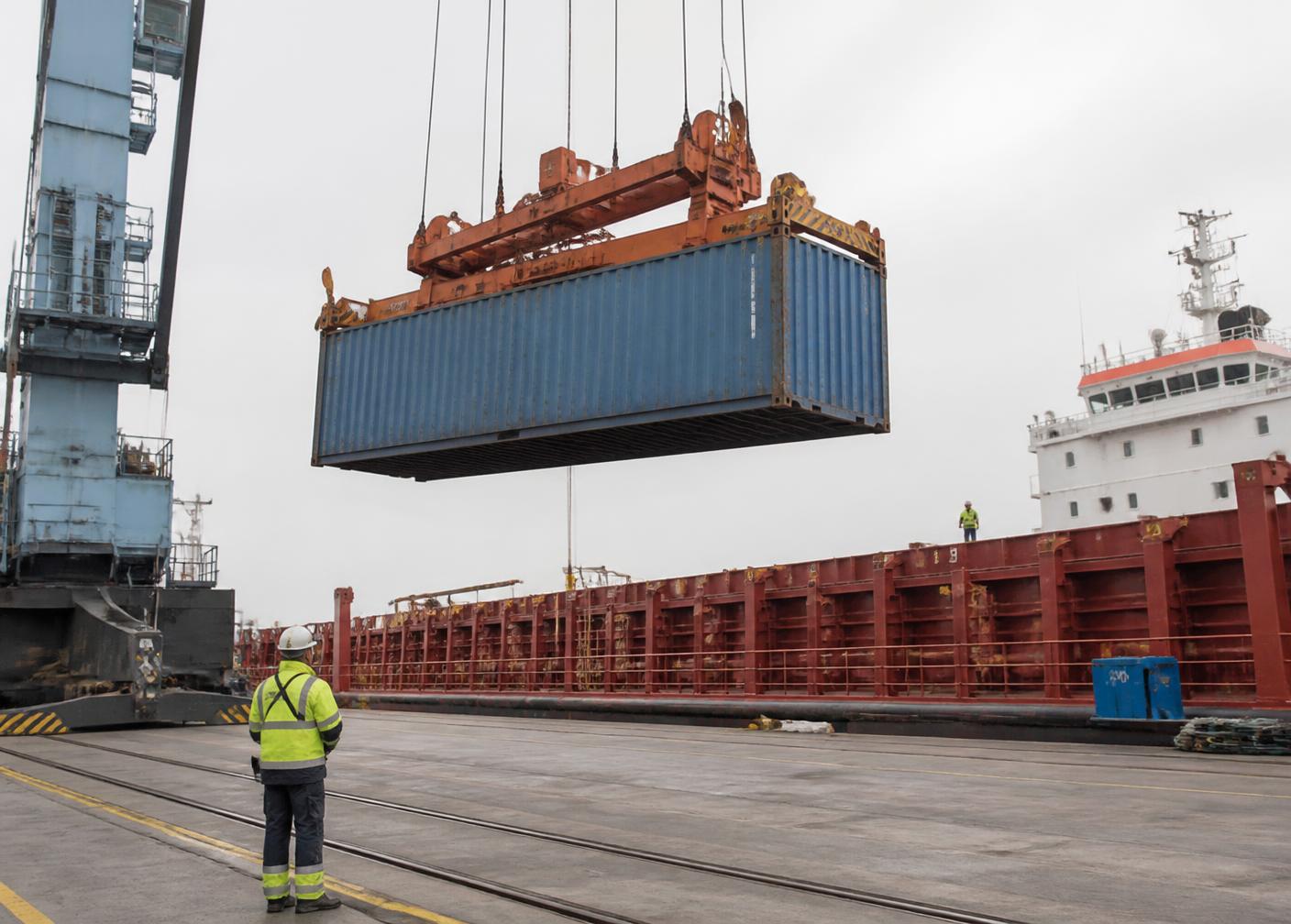 Crane lifting a shipping container over a cargo vessel